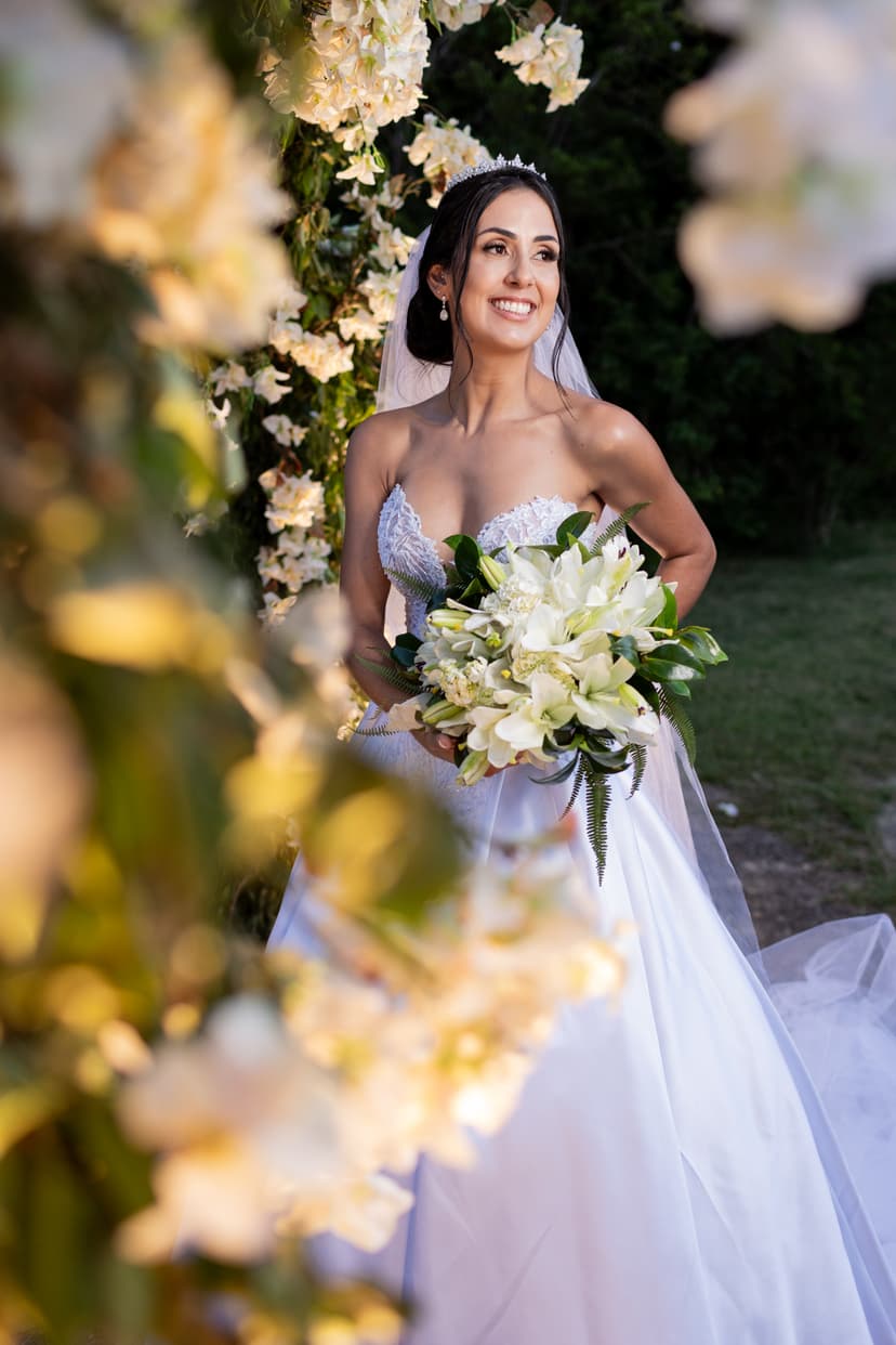 Noiva sorrindo e segurando um buquê de flores